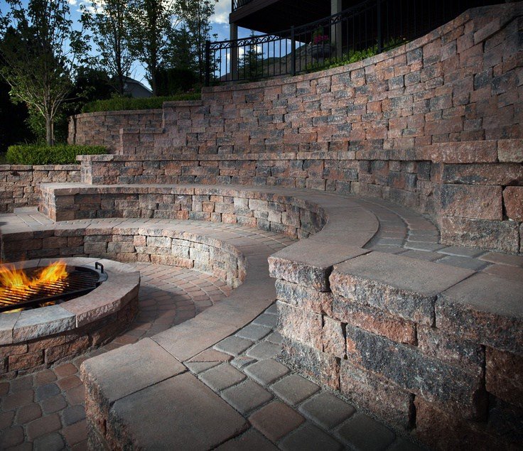 Large retaining wall with a fire pit and seating around the fire pit.