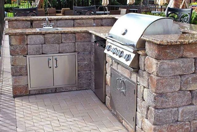 Outdoor grill, sink, and storage space built-in to a stone and granite countertop.
