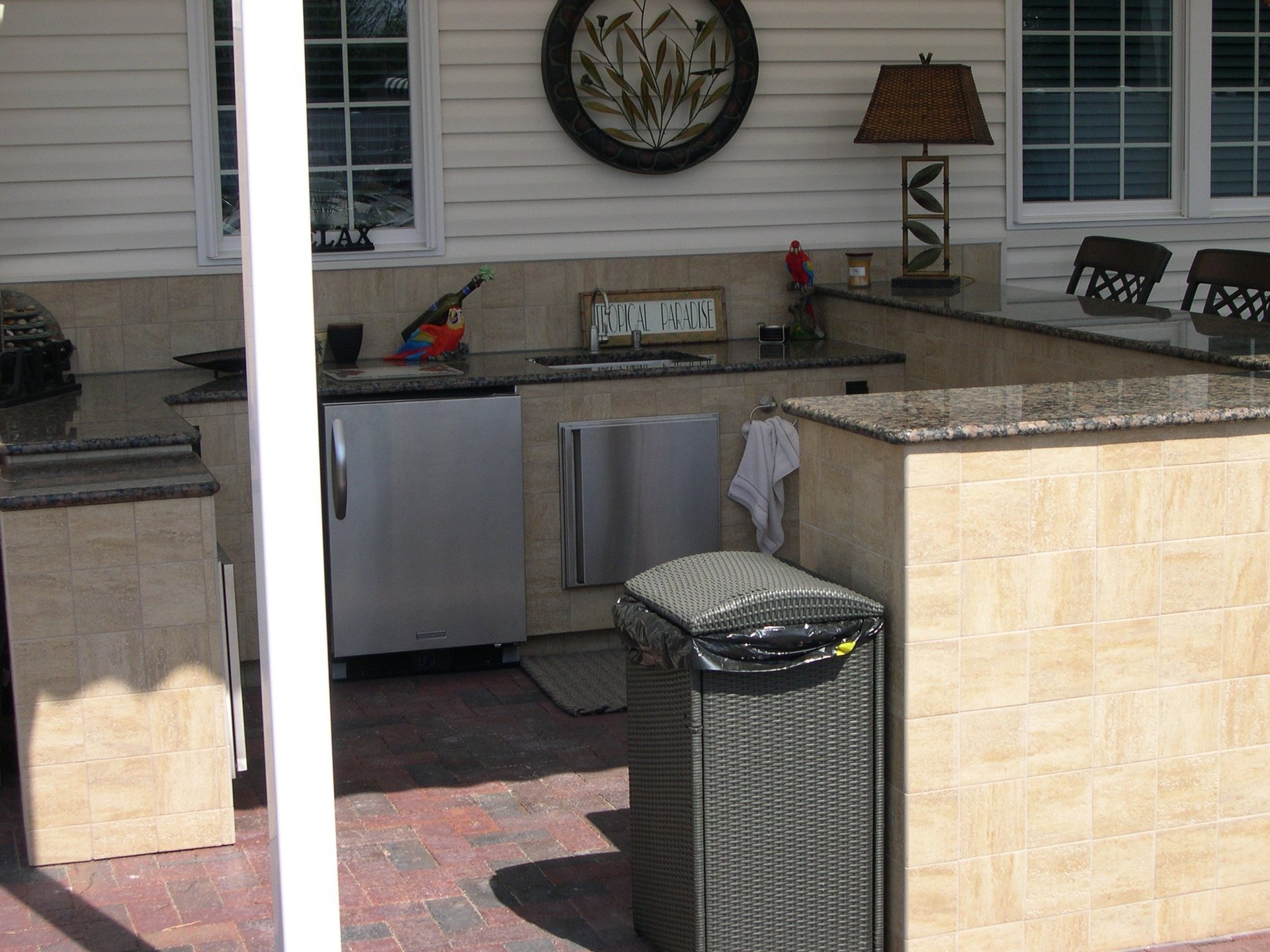 Outdoor kitchen covered by an awning featuring sink, fridge, and storage space..